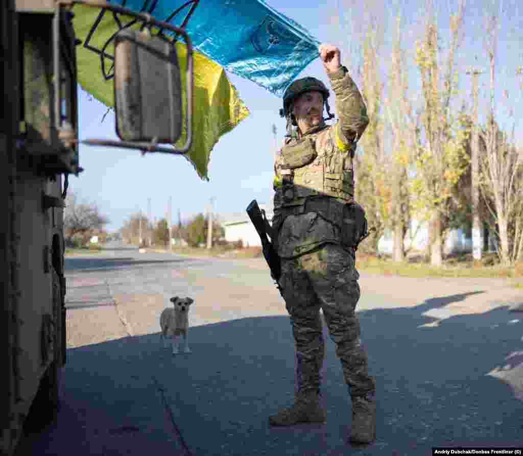 A soldier holds a weathered Ukrainian flag as the sun begins to set on the freshly recaptured town. Snihurivka had been occupied by Russian forces since March. 