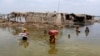 Women carry belongings salvaged from their flooded home after monsoon rains in Pakistan's Sindh Province. 