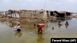 Women carry belongings salvaged from their flooded home after monsoon rains in Pakistan's Sindh Province on September 6. 