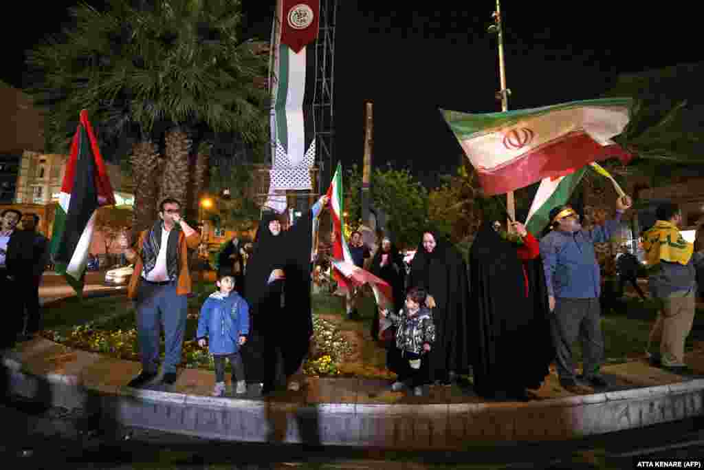 Demonstrators wave Iranian and Palestinian flags as they gather at Palestine Square in Tehran early on April 14. Israel's military said more than 100 drones were launched from Iran, with security sources in Iraq and Jordan reporting dozens seen flying overhead and U.S. officials saying the U.S. military had shot some down.