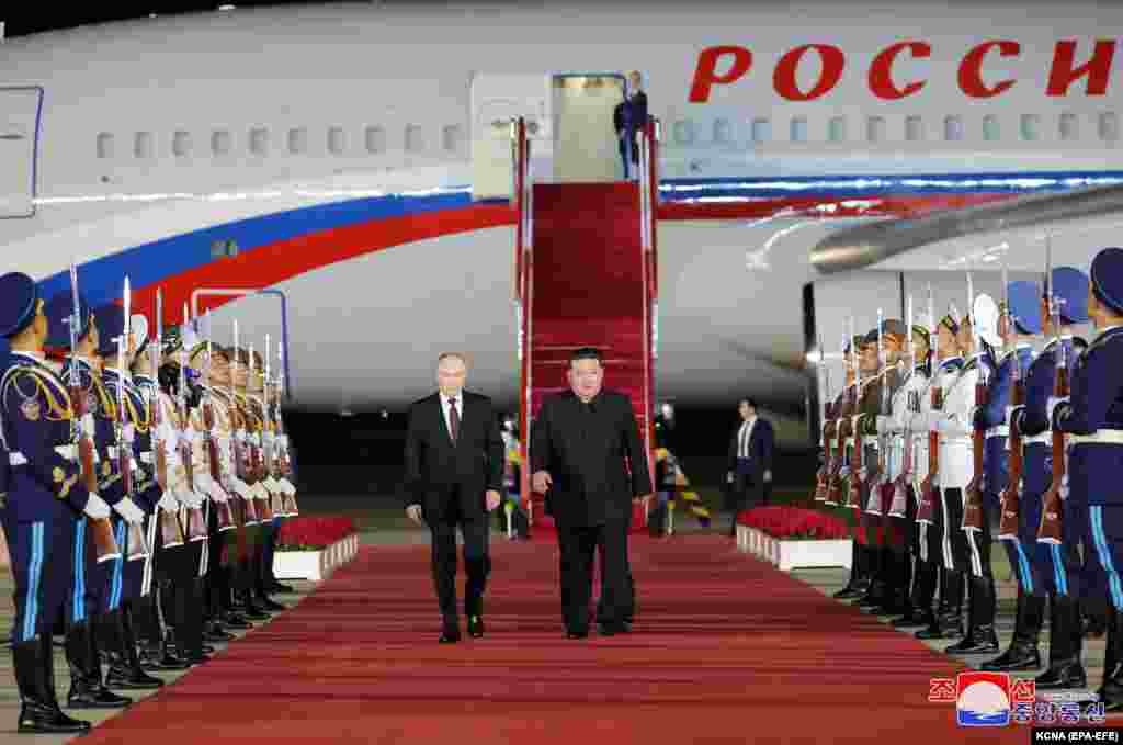 An official photo released by the North Korean Central New Agency (KCNA) shows Putin (left) walking with North Korea's Kim upon his arrival at the airport in Pyongyang. State television showed Kim and Putin shaking hands and repeatedly hugging on the Russian leader's predawn arrival at Pyongyang airport.