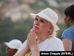 A woman cries in front of the statue of Mary on Apparition Hill on August 3.