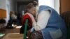 A woman rests her head at a temporary accommodation center for evacuated residents in Volodarskoye, 25 kilometers from the city of Mariupol in Russian-occupied Ukraine, in March 2022. 