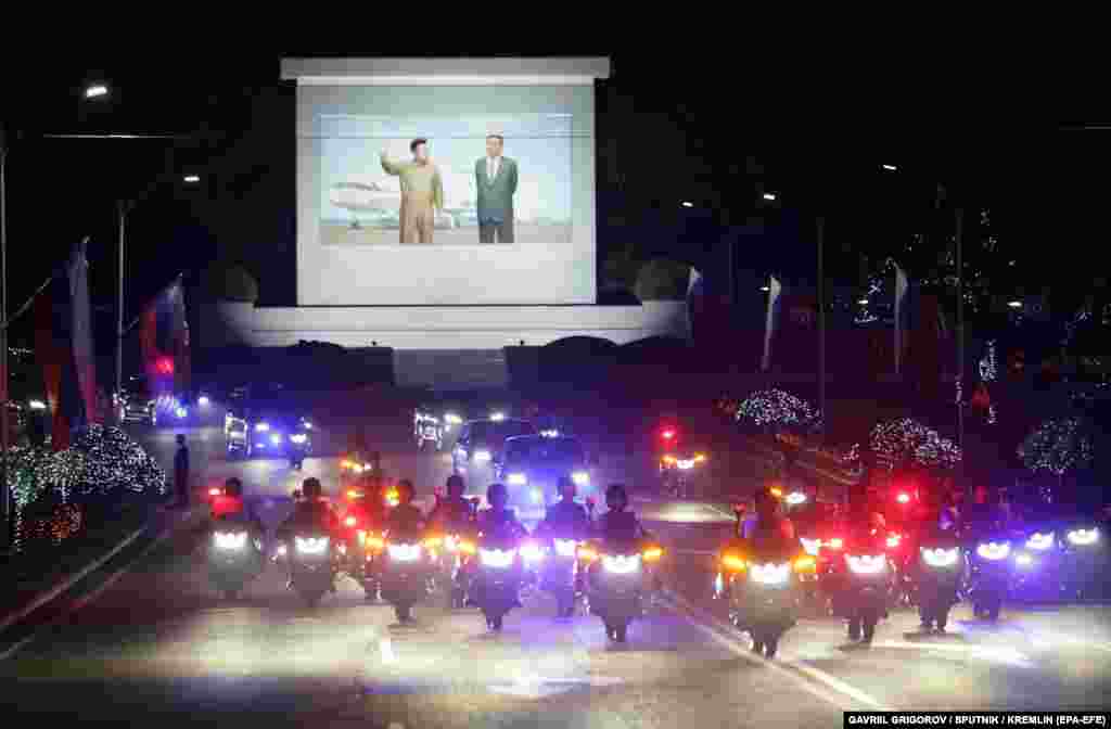 A joint limousine motorcade snakes through the capital decorated with Russian flags and pictures of Putin. 
