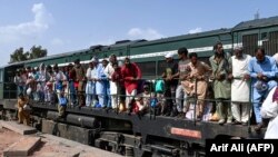 Passengers board a train at a railway station in Lahore on April 20 as they travel back home ahead of the Eid al-Fitr festival marking the end of the holy fasting month of Ramadan.