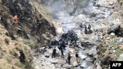 Security officials inspect the wreckage of a vehicle that was carrying Chinese nationals and plunged into a ravine after a suicide attack near Besham city in the Shangla district of Khyber Pakhtunkhwa Province on March 26.
