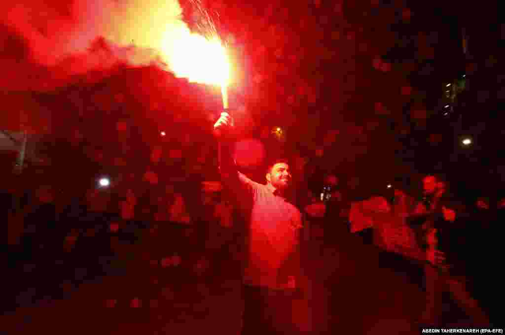 An Iranian man celebrates with a lit flare in Tehran. The attack is the first-ever direct attack on Israeli territory, risking a major escalation as the United States pledged "ironclad" backing for Israel.