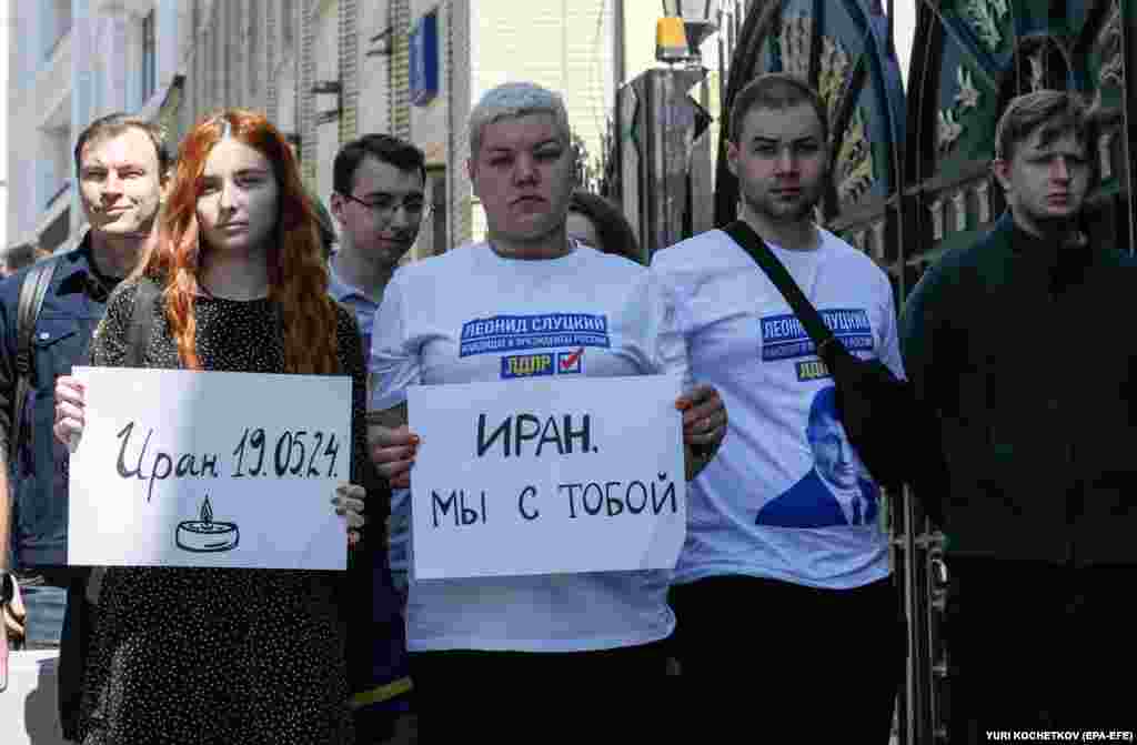 People holds signs reading "Iran - 19.05.2024" (left) and "Iran we are with you" outside the embassy in Moscow.