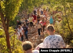 Pilgrims begin the trek up to Cross Mountain as others walk down on the morning of August 4.