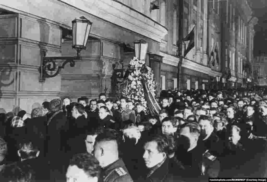 Evening crowds gather to pay their respects to Stalin as he lay in state in the House of the Unions on March 6. Several mourners died in a crush outside the building as crowds gathered to view Stalin's remains. A witness describes crowds shouting to remove trucks that people were being smothered against as one desperate policeman shouted that he had "no instructions" to move one of the vehicles that he was sitting inside.