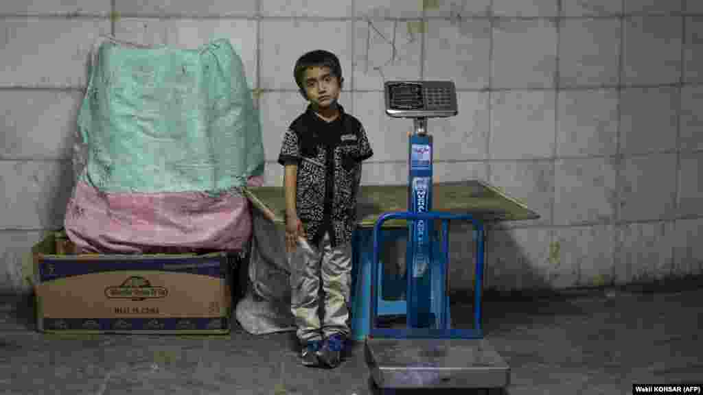 An Afghan boy stands besides a scale while waiting for customers at an underground passageway in Kabul on June 27. Traders in Afghanistan are struggling with sales as the three-day Muslim festival Eid al-Adha, or Festival of Sacrifice, begins on June 28. 
