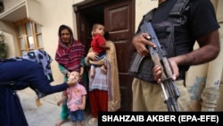 Police escort health workers as they administer polio vaccines to children in Karachi, Pakistan.