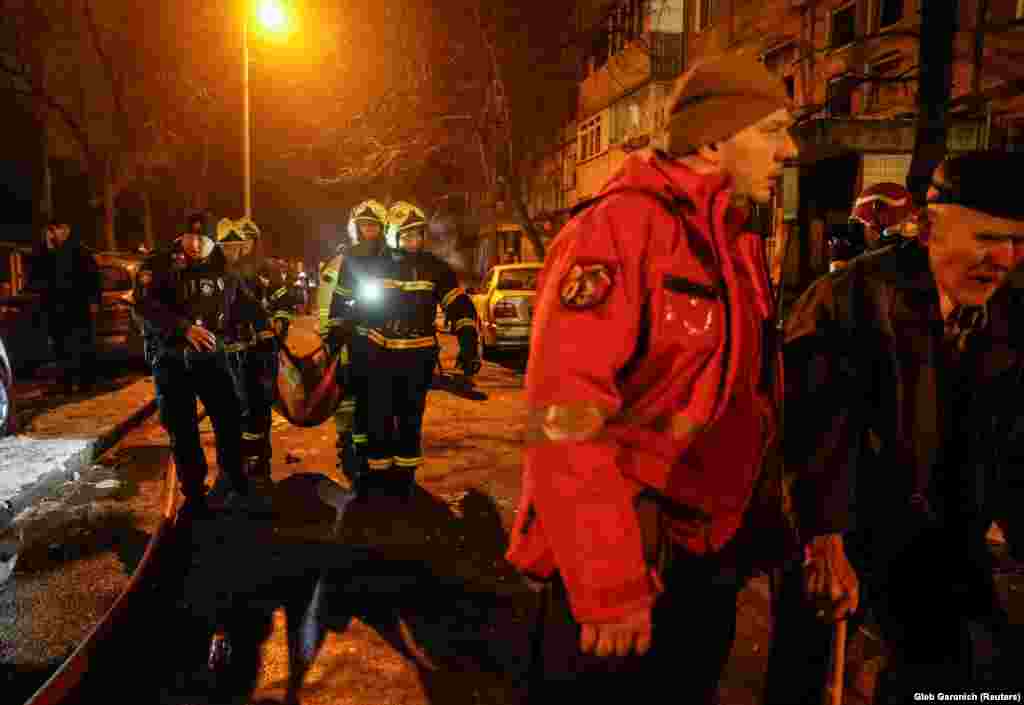 Медики скорой помощи несут раненого жителя в машину. Обломки повредили окна и двери детской больницы в Днепровском районе Киева, пострадавших нет, написал в Telegram'е мэр Виталий Кличко 