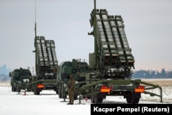 A soldier patrols in front of a U.S. Patriot air-defense system during military training in Poland in February.