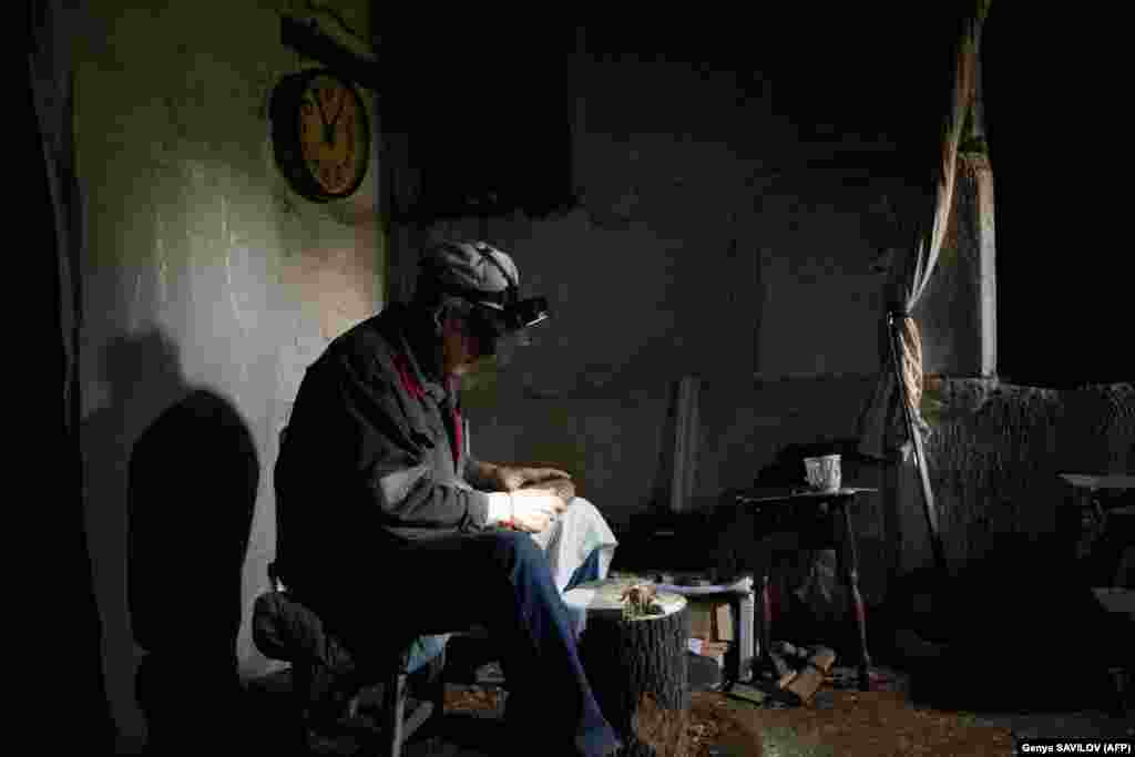 Grozdov's neighbor, 63-year-old Vitaliy Zemin, sits in the cellar, where he lives with his wife. He spends much of his time carving wooden animals while wearing a head torch.