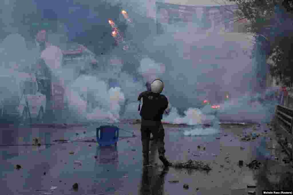 A police officer fires a tear gas shell to disperse Khan's supporters.