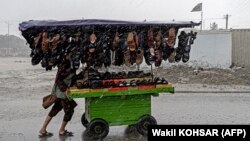 An Afghan vendor pushes a cart of footwear through a street as it rains in Kabul on May 23.