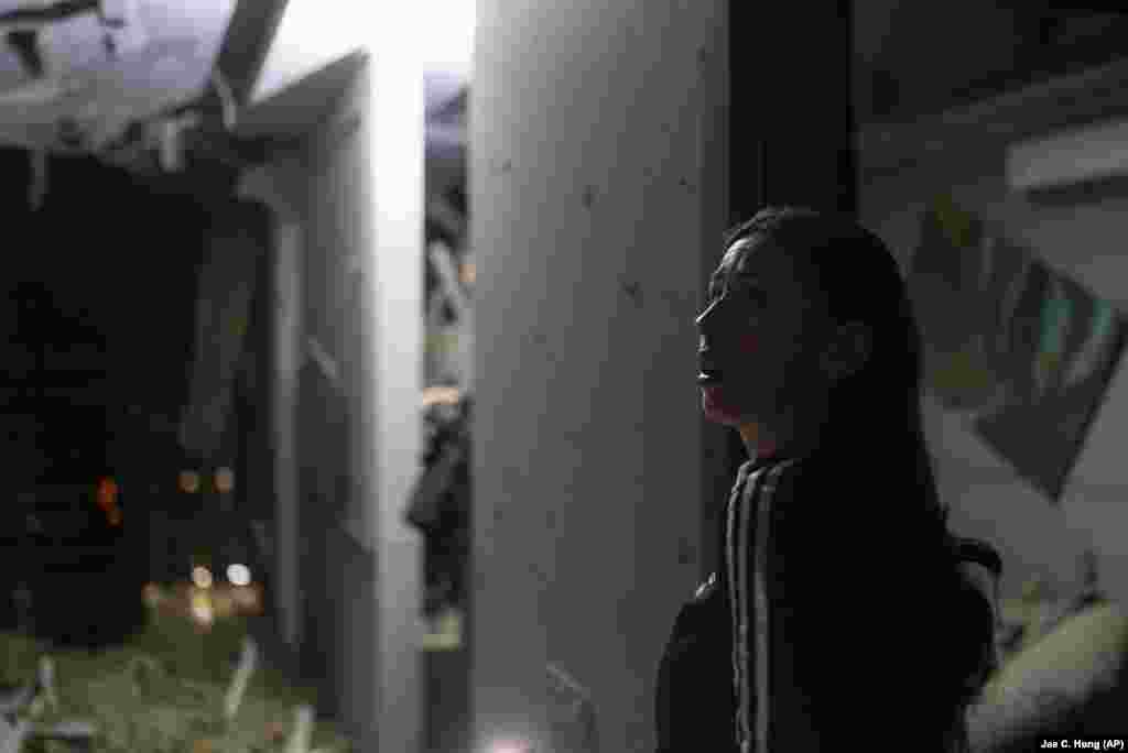 A resident surveys her neighbor's apartment that was damaged during the drone attack.