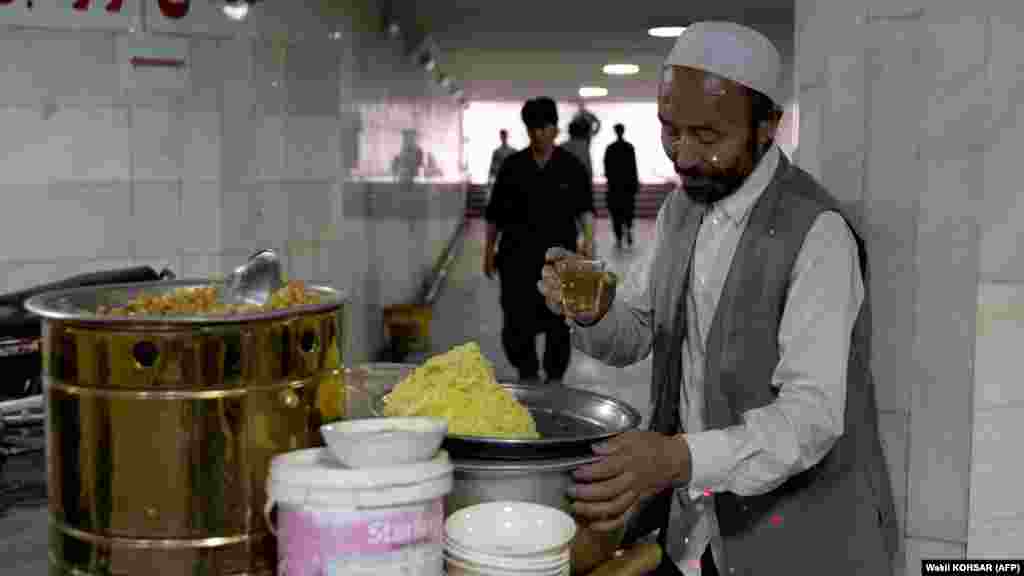 A vendor selling chickpeas takes a tea break while waiting for customers in Kabul. The devastating economic troubles have left many households struggling to buy items needed for Eid celebrations. 