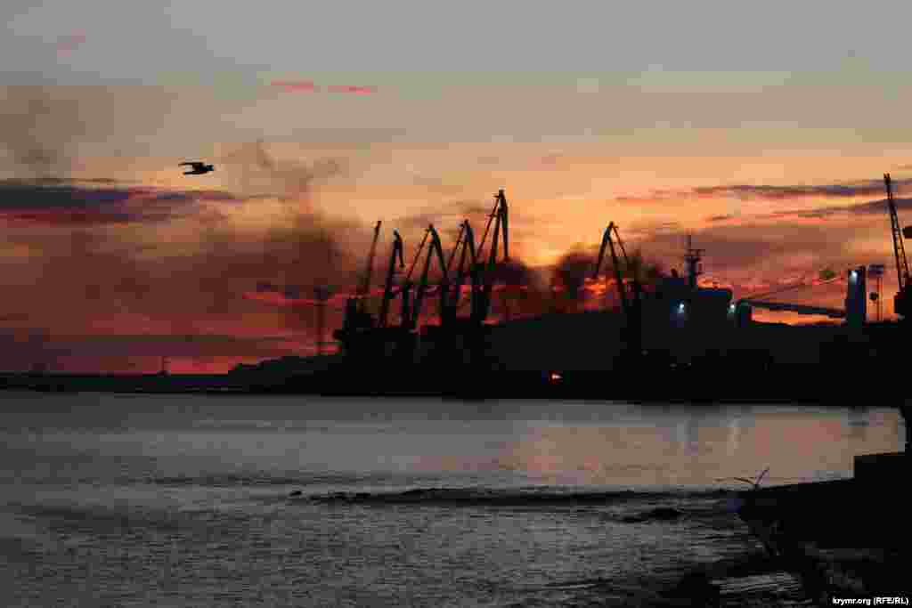 Smoke and flames fill the early morning sky above the port of Feodosia on the eastern coast of the Russian-occupied Crimean Peninsula, following a missile attack that hit a Russian landing ship and claimed at least one life on December 26. Russia's Defense Ministry acknowledged that the Novocherkassk, a naval ship docked there, was damaged.