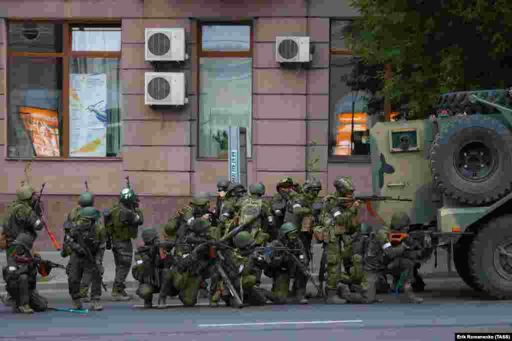 Armed men gather behind a vehicle. At bottom left of the image, a crowbar can be seen. 