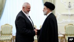 In this photo released by the Iranian president's office, President Ebrahim Raisi (right) greets the leader of the Palestinian militant group Hamas, Ismail Haniyeh, in Tehran on June 20.