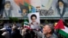 Iranians walk past a mural showing the late revolutionary founder Ayatollah Khomeini (right) Supreme Leader Ayatollah Ali Khamenei (left) and Basij paramilitary forces as they hold posters of Khomeini and Iranian and Palestinian flags in an anti-Israeli gathering after Friday Prayers in Tehran on April 19.
