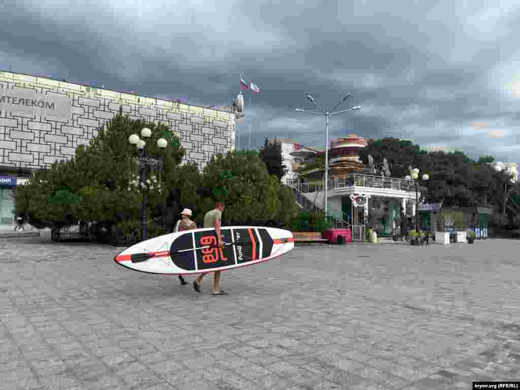 A paddleboarder heads to the beach under dark skies. The diamond-shaped peninsula, which was once a favorite vacation spot for Russian czars and hosted historic summits of world leaders, is struggling to attract tourists to its beaches.