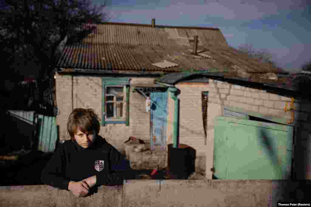 13-летний Никита возле своего дома в селе Татьяновка, расположенном менее чем в 30 километрах от линии фронта в Донецкой области Украины. Для таких детей, как Никита, волонтёры, приходящие несколько раз в неделю, — спасательный круг и единственная возможность общения с кем-то вне своей семьи 