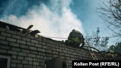 A firefighter sprays water down into Kharkiv resident Viktor's home through the collapsed roof.