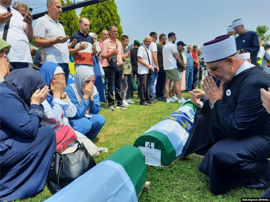 Bosnian Grand Mufti Efendi prays with the families as their relatives' coffins await burial. 