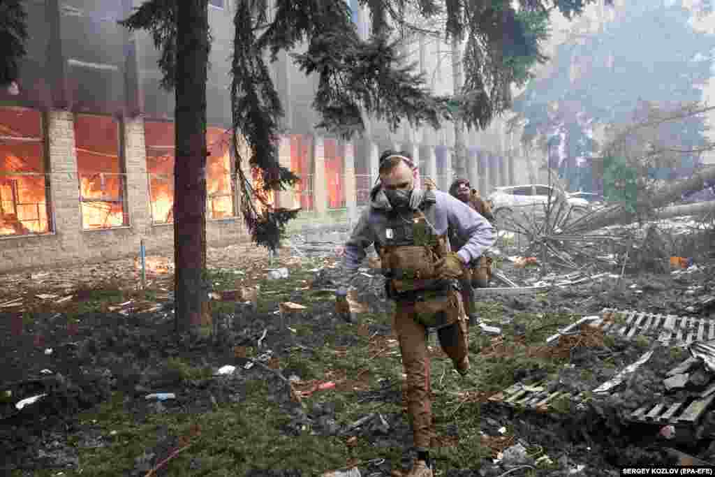 Ukrainian soldiers run near a burning industrial building in the Kholodnohirskiy district of Kharkiv in Ukraine's northeast following a Russian missile attack on March 20. At least three people were killed and at least five were injured, officials said. 