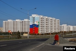 Женщина проходит мимо новопостроенных домов в Мариуполе. Местные жители рассказывают, что новое жилье в основном отдают в ипотеку для жителей РФ