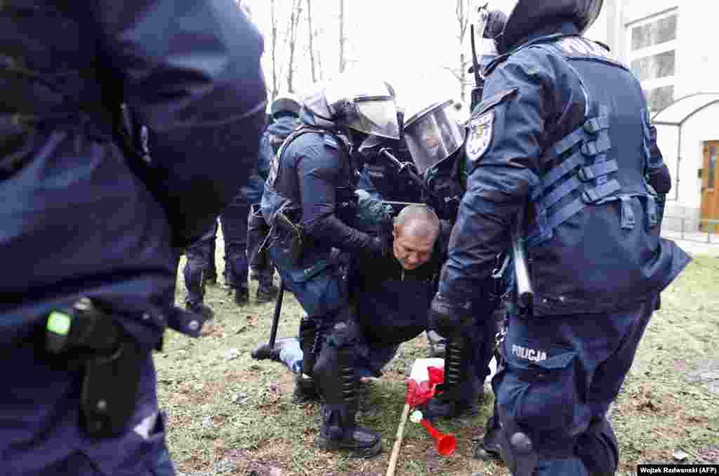 A man is restrained by police during the protests outside the Polish parliament. Twenty-three people were detained during the unrest, in which police deployed pepper spray, batons, and stun grenades according to a Reuters witness. Protesters were seen throwing objects, including cobblestones, at police. 