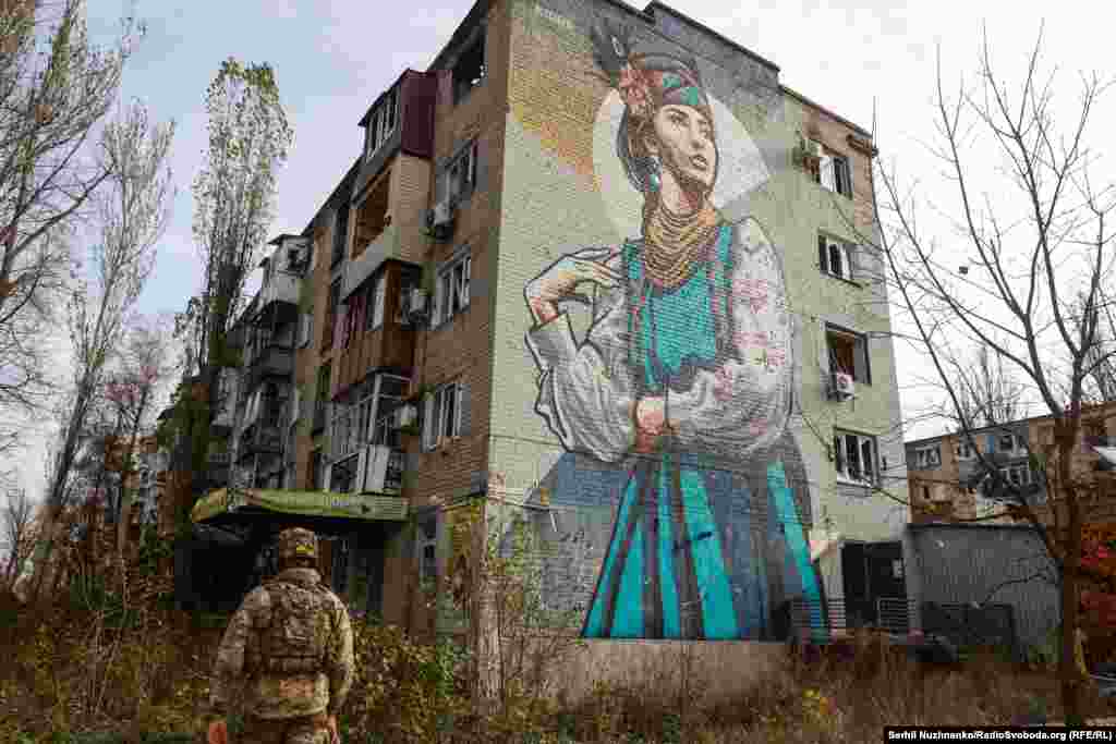 Esger diwaryna,&nbsp;entek uruşdan ozal, bir gyzyň şekli çekilen jaýyň golaýyndan geçip barýar. Donetsk sebitindäki Awdiýiwka şäheri, 2023-nji ýylyň noýabry.