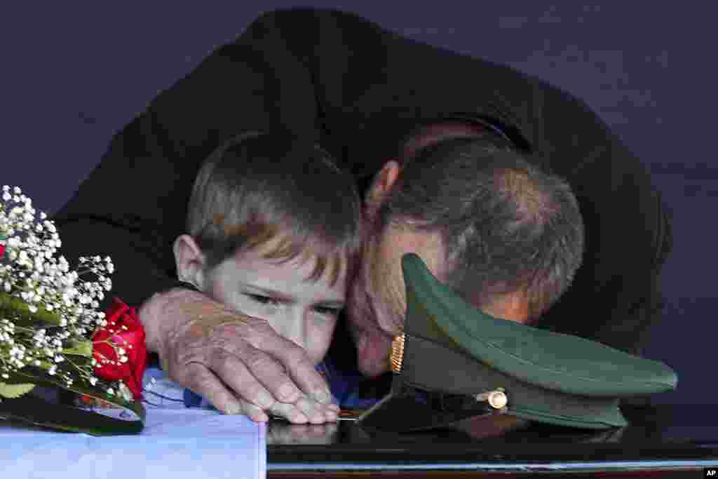 The father and son of Russian Army Sergeant Daniil Dumenko, who was killed during fighting in Ukraine, mourn at his funeral in Volzhsky, near Volgograd, Russia, on May 26. 