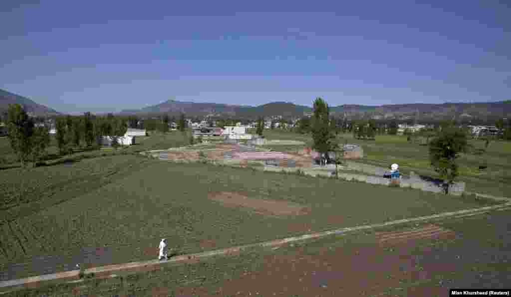 A man walks in 2012 near the the place where bin Laden’s compound used to stand. Satellite images from 2021 show dozens of new houses have been built in the neighborhood since 2011, but the former site of the compound remains empty and has been used by locals to play cricket.