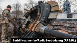 A Ukrainian servicemember inspects the remains of a destroyed Russian tank in the village of Lukyanivka, near Kyiv, on March 27.