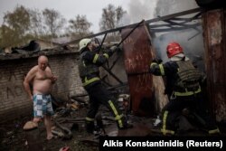 Tűzoltók dolgoznak egy lebombázott garázsnál Harkivban egy orosz támadás után 2022. április 18-án