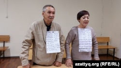 Гражданские активисты Маруа Ескендирова и Амангельды Оразбаев на суде по их делу с плакатами, на которых перечислены сутки, в которые они в разное время отбывали административные аресты. Уральск, 7 октября 2022 года