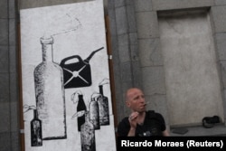Zinkivskiy stands on a street as he works on his new painting in Kharkiv on May 16. He later added the words "Hellish hospitality" to the work.