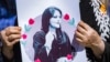 A woman holds a poster depicting Mahsa Amini during a protest following her death last year.