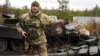 Военнослужащий Украины показывает эмблему элитного подразделения войск России возле уничтоженных российских танков в селе Дмитровка под Киевом, 2 апреля 2022 года
