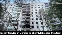 Firefighters and a police officer work at the site of an apartment building damaged during Russian strikes on Chernivtsi, Ukraine, July 12, 2025.