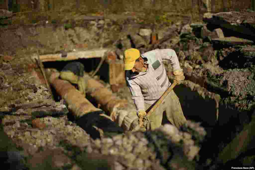 Workers repair a central heating pipe in the Saltivka neighborhood of Kharkiv on October 15. Authorities are working to gradually restore electricity to the area in the coming days, and repairs to water and gas infrastructure will come next, according to Roman Semenukha, a deputy with the Kharkiv regional government. "Only after that will we be able to begin to restore heating," he said. 