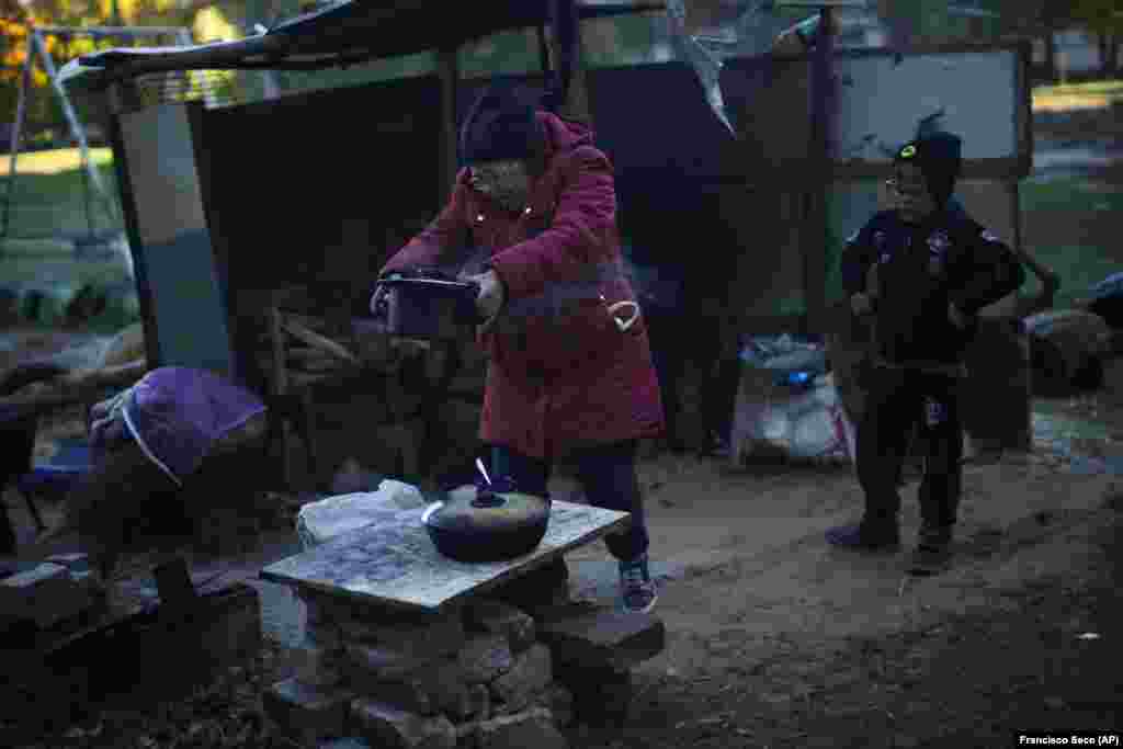 Iryna Panchenko removes a pot of food from a makeshift stove next to her 9-year-old grandson Artem in Kivsharivka. "It's cold and there are bombings," Artem said as he helped his grandmother with the cooking next to their nearly abandoned apartment block. Located north of Donetsk, Kivsharivka's residents have been living without gas, water, or electricity for nearly three weeks following Russian missile strikes that cut off the town's utilities. 