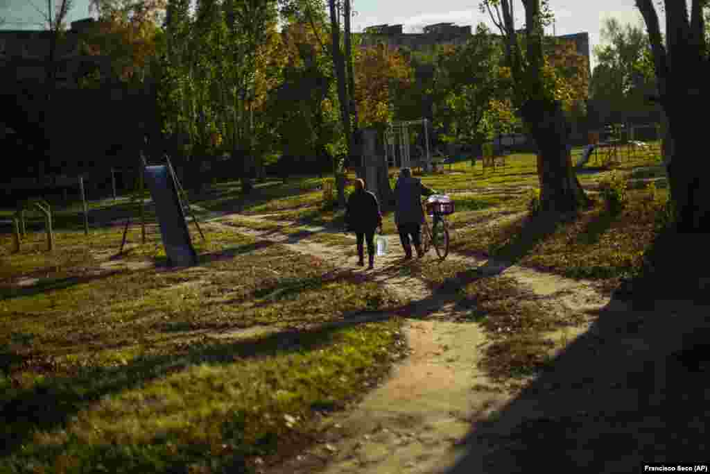 Locals in Kivsharivk carry plastic bottles of water after filling them up at a local well. Authorities in the Ukrainian-controlled areas have urged all remaining residents to evacuate, and warned that gas and water services in many areas will likely not be restored by winter.