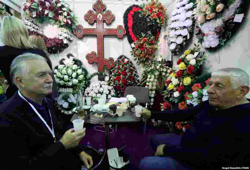 Двајца мажи разговараат пред штандот на погребалниот дом Ника. Настаните на изложбата вклучуваат час за балсамирање, лекција за „ритуално цвеќарство“ и час посветен на правните сложености во управувањето со погребот.