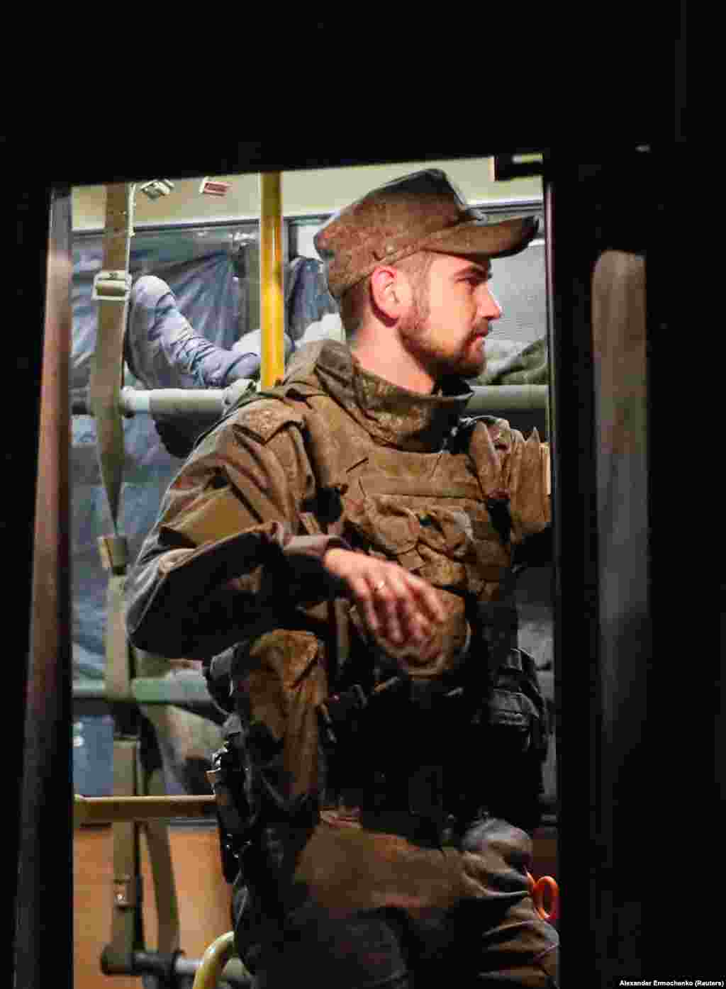 A separatist fighter stands guard over a bus carrying wounded Ukrainian soldiers from Mariupol. 