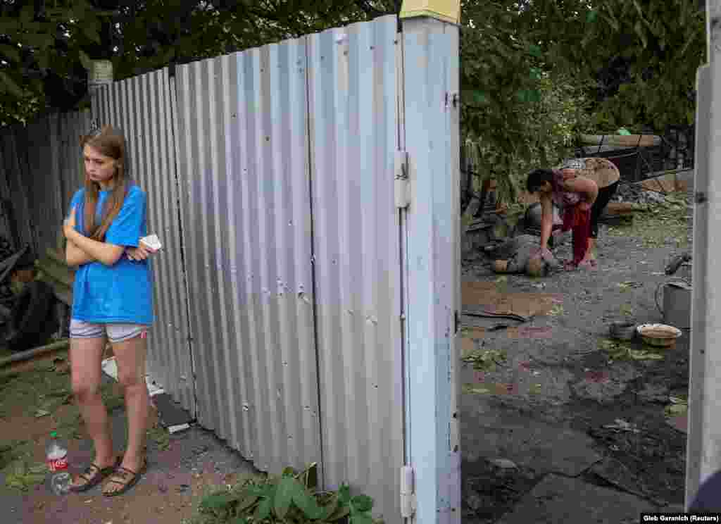 A young girl waits as a woman caresses the body of her mother-in-law, who was killed during a Russian military strike on Kostyantynivka on July 9.